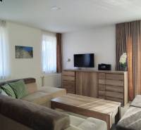 Világos szoba a házikóban kényelmes kanapéval és fa mintázatú padlóval.