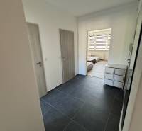 Előszoba egy háromszobás lakásban sötét burkolattal és világos ajtókkal.