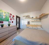 Hálószoba családi házban ággyal, polcokkal, képekkel és fa dekorációs padlóval.