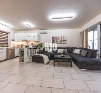 Világos nappali családi házban konyhával és nagy kanapéval.