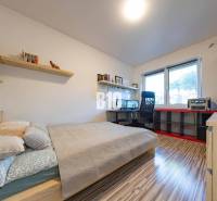 Hálószoba családi házban íróasztallal, polcokkal és fa dekorációjú padlóval.