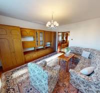 Nappali egy családi házban, fa nappali szekrénnyel és mintás ülőgarnitúrával.