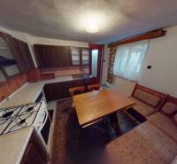 Konyha egy családi házban fa szekrényekkel, tűzhellyel és étkezőasztallal.