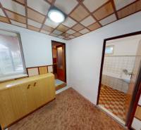 Családi ház belső tere fa dekorációjú padlóval, szekrénnyel és fürdőszobába vezető bejárattal.