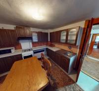 Családi ház konyhája fa bútorokkal, asztallal és háztartási gépekkel.