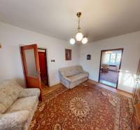 Családi ház nappalija színes szőnyeggel, kanapékkal és fa nappali szekrénnyel.