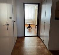 Háromszobás lakás folyosója fa dekor padlóval, amely világos helyiségbe vezet.