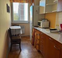 Konyha egy 3 szobás lakásban, fa dekor padlóval és meleg színű bútorokkal.