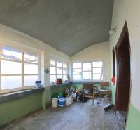 Családi ház belső tere régi ablakokkal és betonpadlóval.