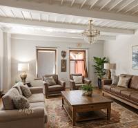 Nappali családi házban bőrkanapéval, fa dekoros padlóval és szőnyeggel.