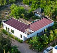 Házak építése Paje-ban, Unguja déli régiójában, piros tetővel, zölddel körülvéve.