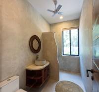 Fürdőszoba mosdóval, kerek szőnyeggel és ventilátorral. Házépítés.