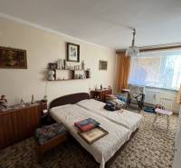 Szoba egy háromszobás lakásban kisággyal, szőnyeggel és bútorokkal, dekorációkkal a falakon.