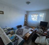 Nappali egy háromszobás lakásban fa dekor padlóval és bútorokkal.