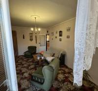 Nappali egy háromszobás lakásban zöld bútorokkal és dekoratív szőnyeggel.