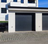 Garázsok a Predmerského utcában Trencsénben, háttérben egy lakóházzal.