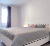 Hálószoba egy kétszobás lakásban világos bútorokkal és fa dekorációjú padlóval.