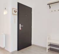 Előszoba világos falakkal és fa dekorációjú padlóval, amely a hálószobába vezet.