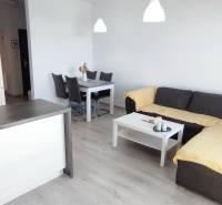 Nappali egy kétszobás lakásban konyhával, kanapéval és étkezőasztallal, fa dekorációjú padlóval.