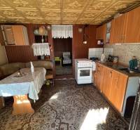 Konyha régi bútorokkal, fa mintázatú padló, látható étkező rész.