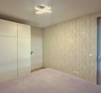 Hálószoba egy kétszobás lakásban nagy szekrénnyel és erkélyajtókkal.