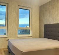 Hálószoba nagy ablakkal és ággyal egy kétszobás lakásban, fa dekorációjú padlóval.