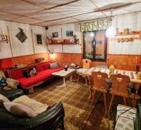 Hangulatos belső tér egy faházban, díszített asztallal, kanapéval és fa székekkel.