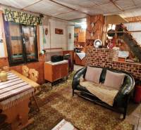 A ház belseje kanapéval, fa dekorációjú padlóval, étkezőasztallal és lépcsővel.