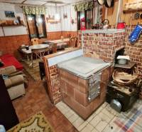 Egy hagyományos téglakályhával, fa dekorációjú padlóval és kényelmes ülőhellyel rendelkező házikó belső tere.