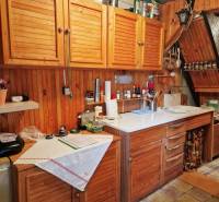 Konyha faházban fa szekrényekkel és fehér munkalappal, otthonos légkör.