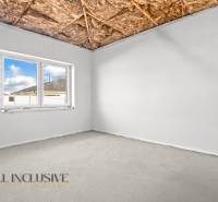 Szoba ablakkal, csupasz mennyezettel és látszóbetonnal egy családi házban.