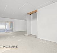 Tágas szoba egy családi házban befejezetlen padlóval és nagy ablakkal.