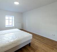 Hálószoba ággyal és fa dekorációjú padlóval egy kétszobás lakásban.