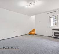 Nappali szőnyegpadlóval, ablakkal és lépcsővel egy családi házban.