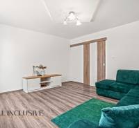 Családi ház belső tere fa dekoros padlóval, zöld kanapéval és asztallal.