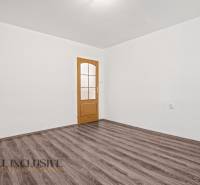 Fehér belső tér fa dekorációjú ajtóval és padlóval egy családi házban.