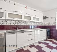 Konyha családi házban fehér szekrényekkel, lila csempékkel és beépített készülékekkel.