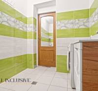 Fürdőszoba családi házban színes csempékkel, faajtókkal és mosógéppel.