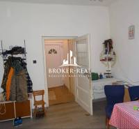 Családi ház belső tere fa dekorációjú padlóval, étkezőasztallal és ruhafogassal.