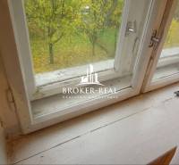 Kilátás egy családi ház ablakából egy őszi kertre és egy fára.