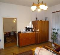 Nappali egy családi házban fa szekrényekkel, kanapéval és virággal.