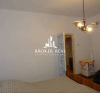 Családi ház hálószobája egyszerű berendezéssel és retro fűtéssel.