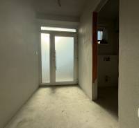 Családi ház belső tere fehér falakkal és üvegajtókkal a folyosó végén.