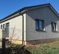 Családi ház Tesárske Mlyňany-ban szürke homlokzattal és ablakokkal, kerítéshálóval körbekerítve.