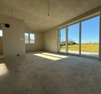 Tágas családi ház belső tér nagy ablakokkal és kilátással a kertre.