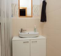 Fürdőszoba tükörrel és mosdóval a szekrény felett egy kétszobás lakásban.