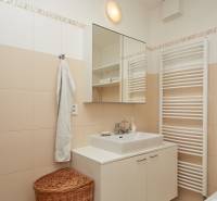 Fürdőszoba egy kétszobás lakásban fehér bútorokkal, tükörrel és törölközővel.