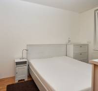 Hálószoba egy kétszobás lakásban franciaággyal, éjjeliszekrénnyel és komóddal.