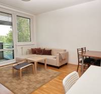 Nappali kanapéval, étkezőasztallal és fa dekorációjú padlóval egy kétszobás lakásban.