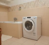 Fürdőszoba káddal, mosógéppel és polccal egy kétszobás lakásban.